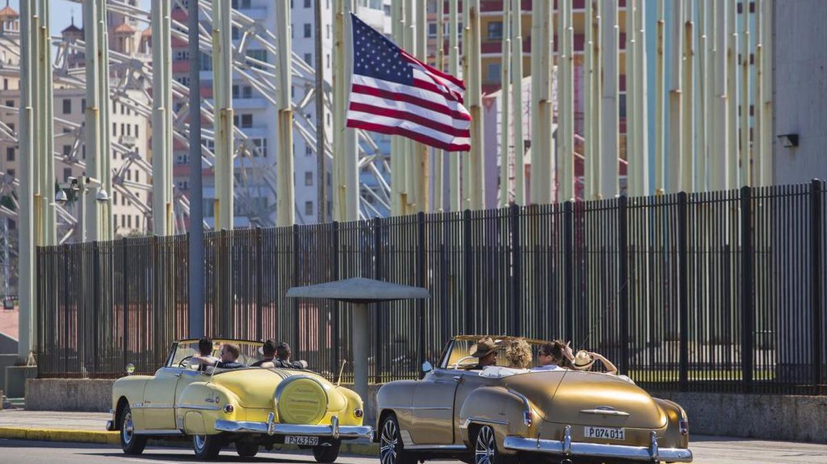 Turistas en autos norteamericanos antiguos pasan junto a la embajada de Estados Unidos en La Habana, a principios del 2016. 