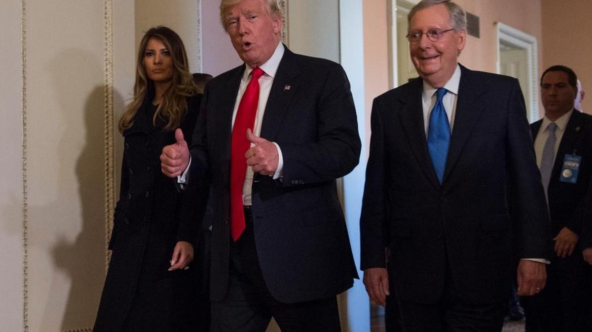 El presidente electo Donald Trump (centro), junto a su esposa, Melania, y el líder de la mayoría del Senado, Mitch McConnell, visita el Capitolio de Washington el jueves.