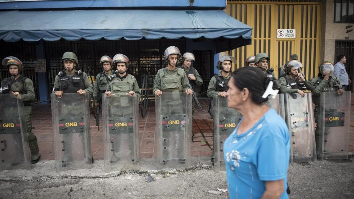 Una mujer pasa frente a soldados venezolanos que custodian propiedades saqueadas en Táchira, el domingo pasado.
