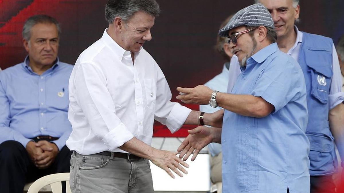 El presidente de Colombia, Juan Manuel Santos (izq.), le estrecha la mano al jefe de las FARC, Rodrigo Londoño, también conocido como Timochenko, en la culminación del desarme de la guerrilla en Buenavista, el pasado 27 de junio.