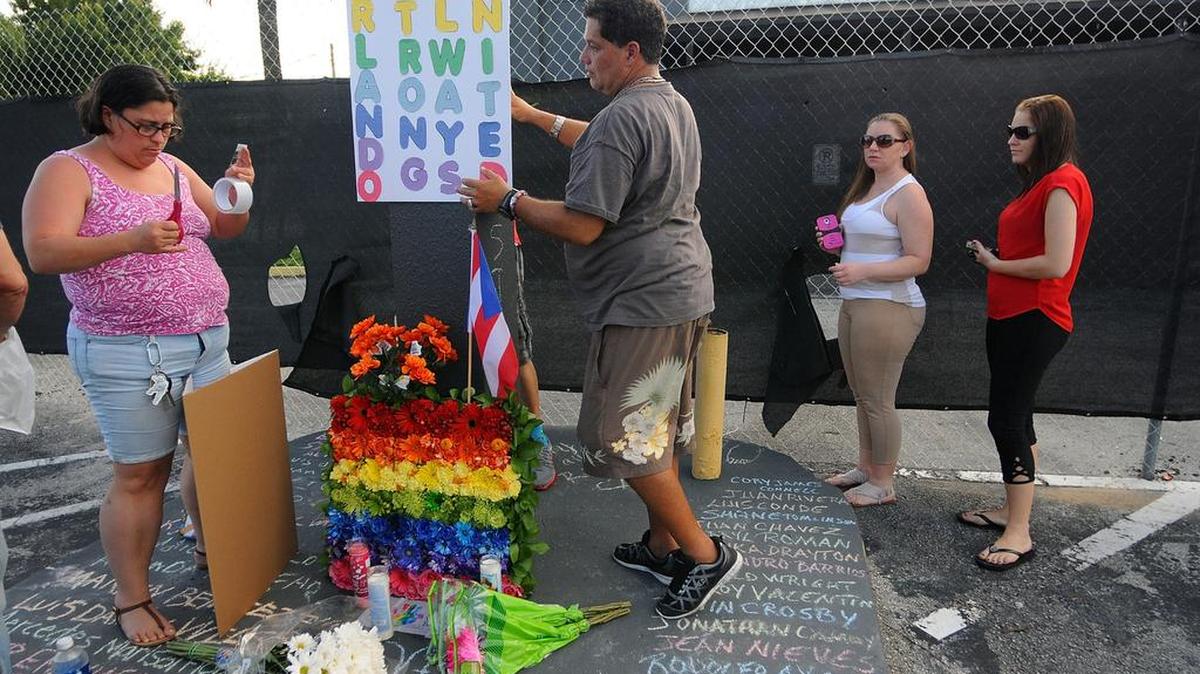 Varias personas dejan carteles y flores por las víctimas de la matanza en el club gay Pulse, en Orlando, el pasado 21 de junio, en el exterior del centro nocturno.