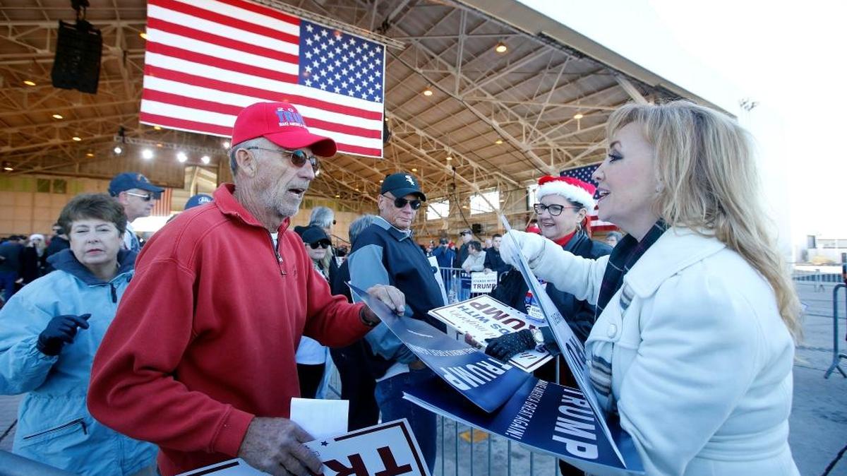 Una voluntaria reparte carteles de la campaña del candidato republicano Donald Trump en Mesa, Arizona.