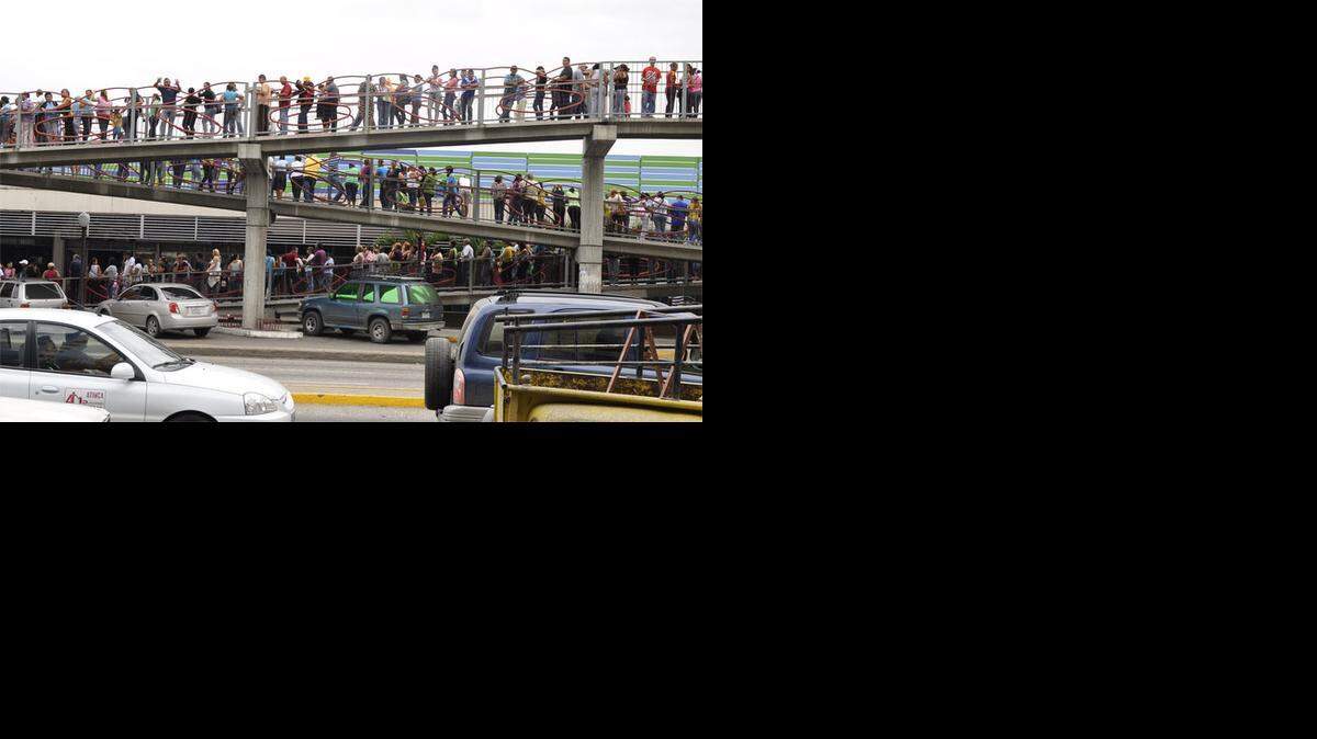 
Venezolanos hacen una larga fila para acceder a un supermercado en Caracas para comprar los insumos básicos.
