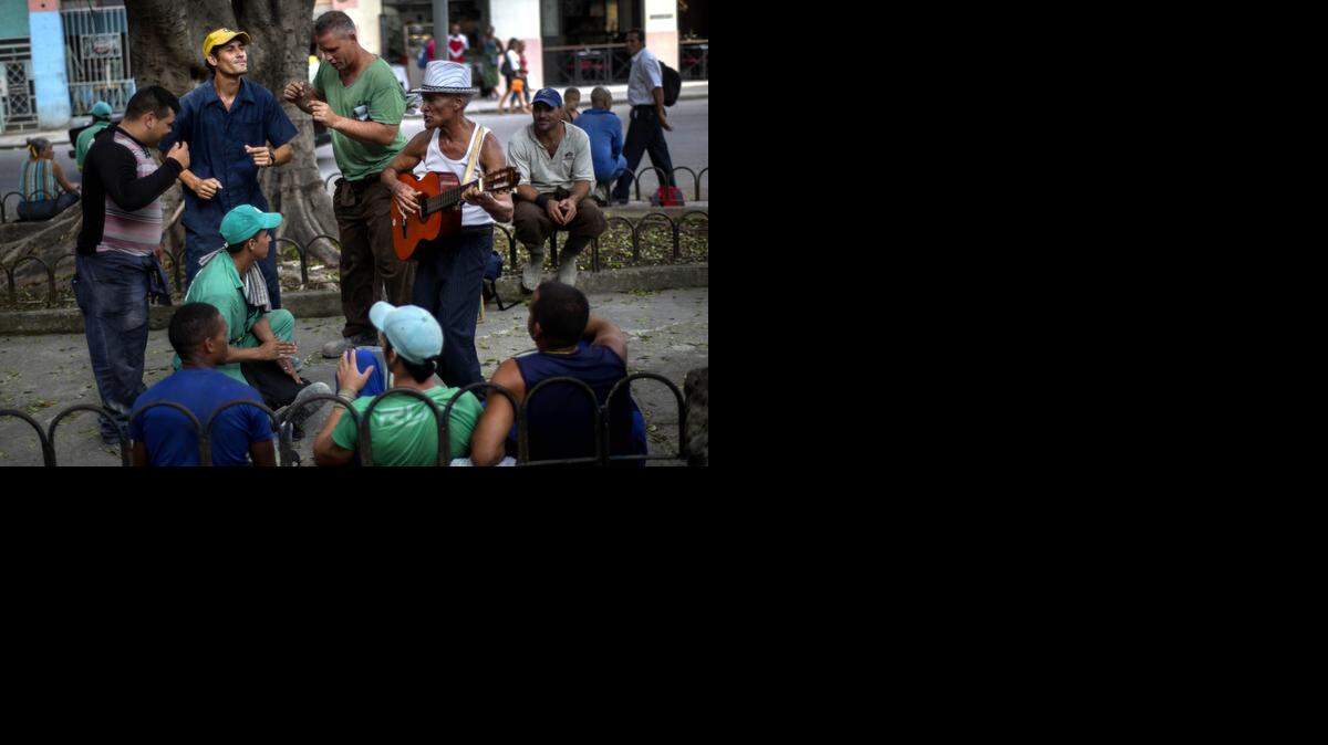 
Obreros de la construcción bailan y cantan con un músico callejero mientras esperan el autobús en una calle de La Habana, la semana pasada.
