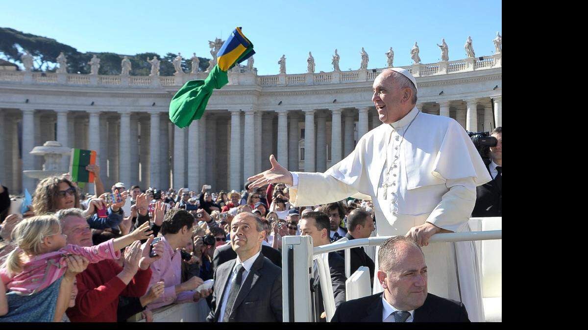 
El Papa Francisco toma una bandera brasileña que le lanzó un devoto a su llegada el miércoles a la Plaza de San Pedro. Francisco visitará Cuba este año.

