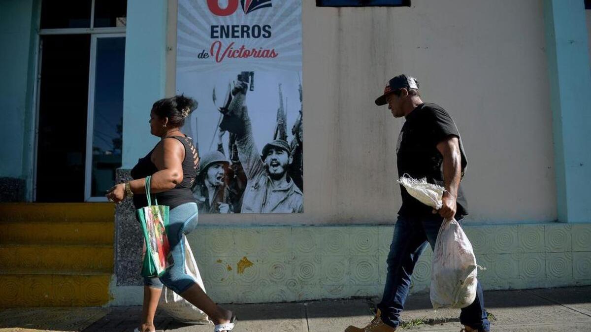 Dos personas caminan por un afiche que conmemora los 60 años de la revolución cubana, el lunes en La Habana.