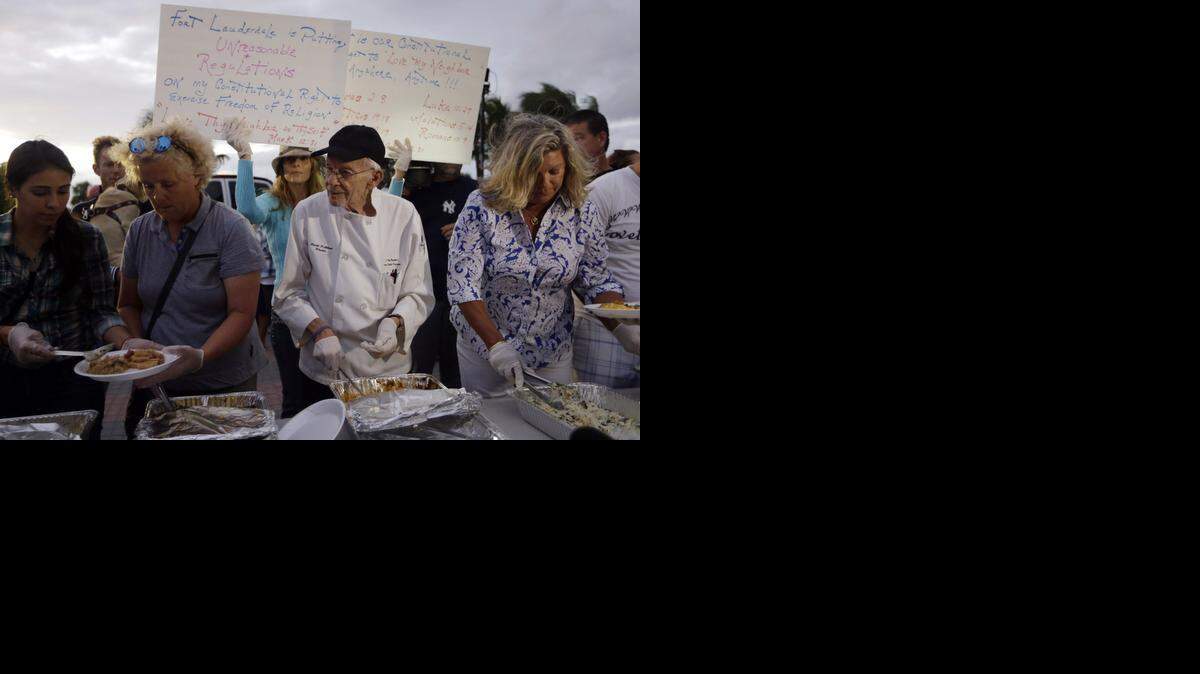 
El activista Arnold Abbott (centro), de 90 años de edad, sirve comidas a los desamparados en un parque público de Fort Lauderdale, cerca de la playa.
