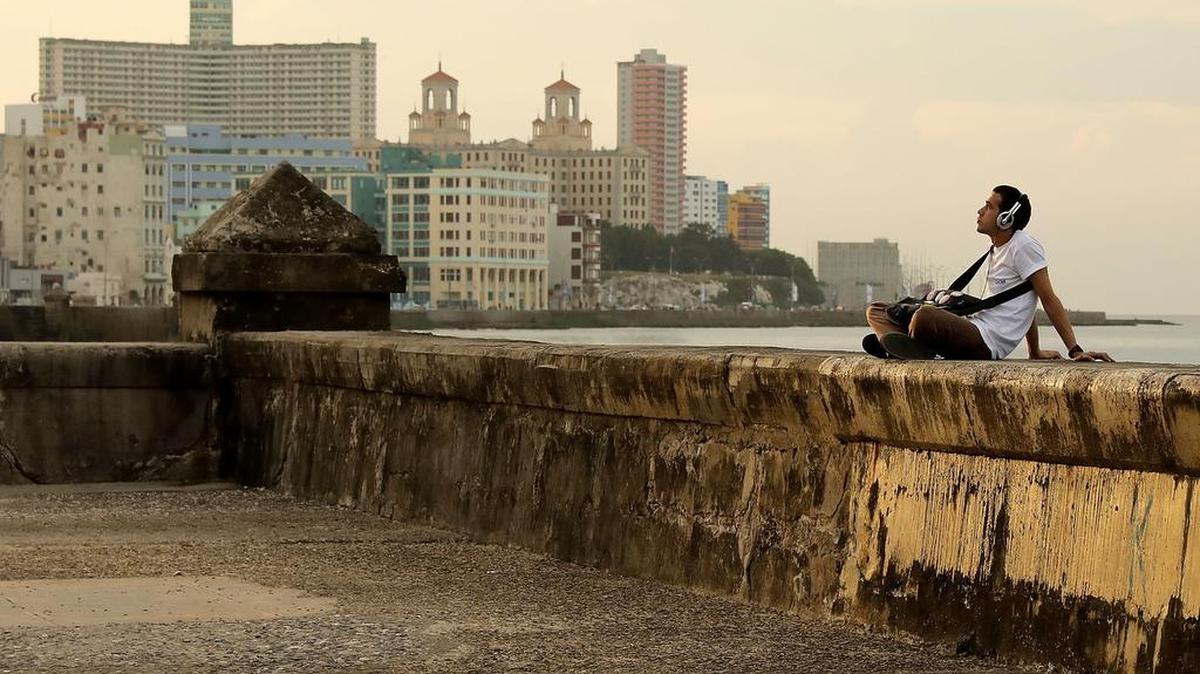 Un hombre escucha música sentado en el famoso muro del Malecón, en La Habana.