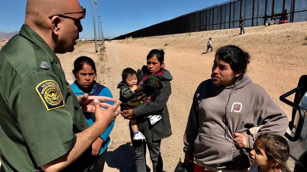 El agente de frontera Joe Romero habla con una mujer de Guatemala que, junto a sus hijos, cruzó la frontera y se entregó a las autoridades, en el área de Ysleta, cerca de El Paso, Texas, el 6 de marzo.