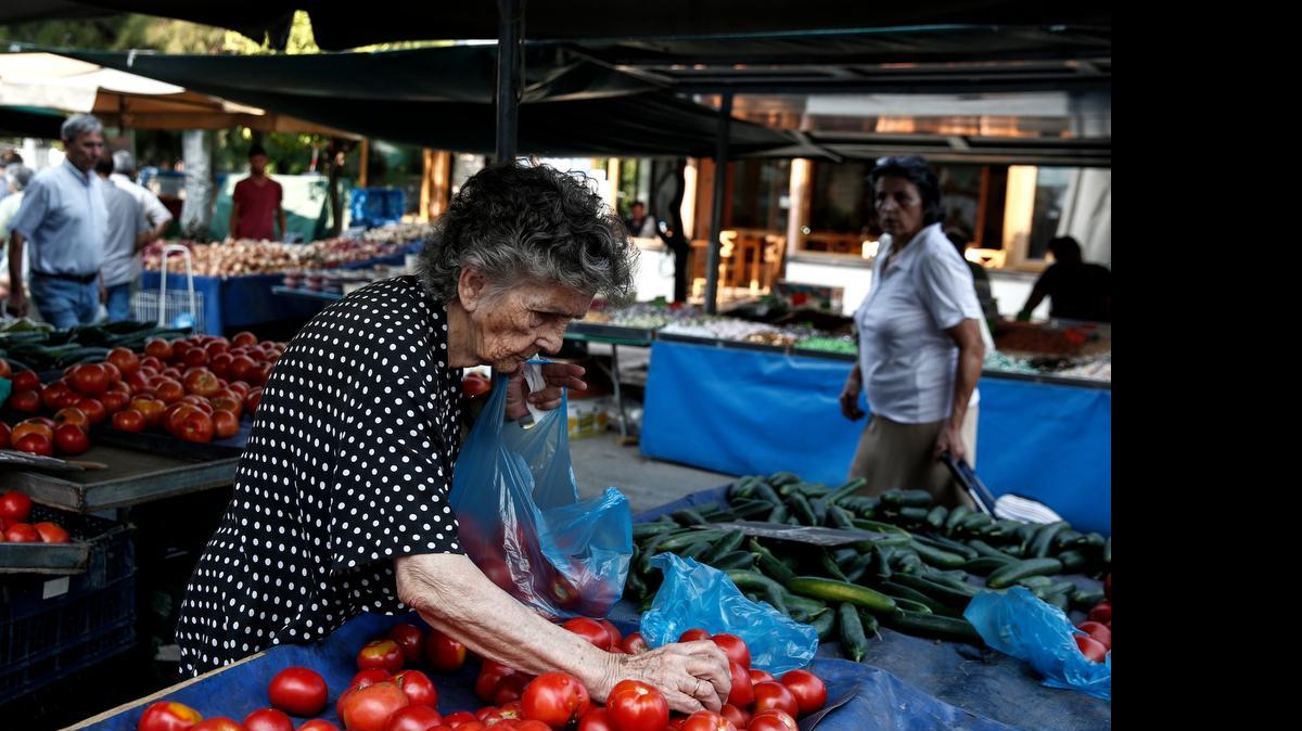 
Una mujer de la tercera edad escoge tomates en un mercado de Atenas. La crisis ha golpeado a los pensionados en Grecia.
