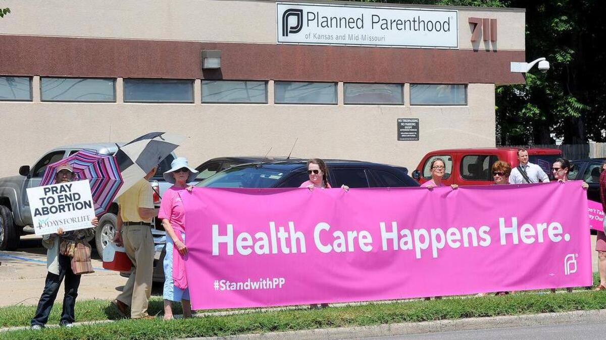 
Cinco mujeres muestran un pancarta en apoyo a los servicios de salud que presta Planned Parenthood en Kansas y parte de Missouri, mientras un hombre sostiene una pancarta en contra del aborto, el 28 de julio. 



