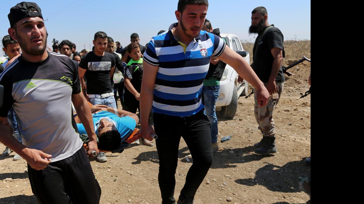 
Varios palestinos transportan a un joven herido en choques con el ejército israelí durante una protesta en Gaza el viernes pasado.
