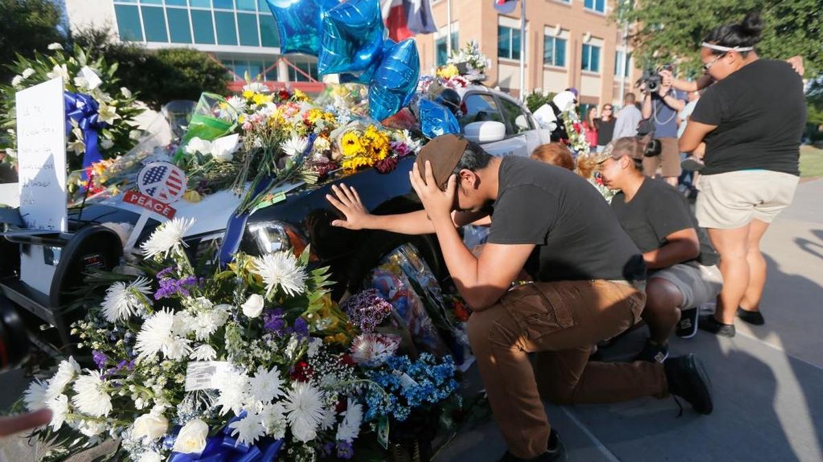 Varias personas recuerdan en un tributo improvisado frente al Departamento de Policía de Dallas a los policías asesinados.