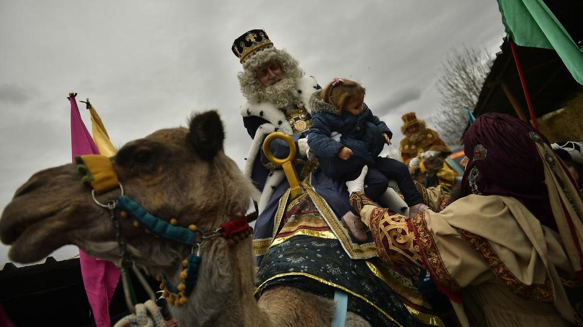 Un hombre disfrazado de uno de los tres Reyes Magos carga a una niña en un desfile en la ciudad española de Pamplona, el 5 de enero.