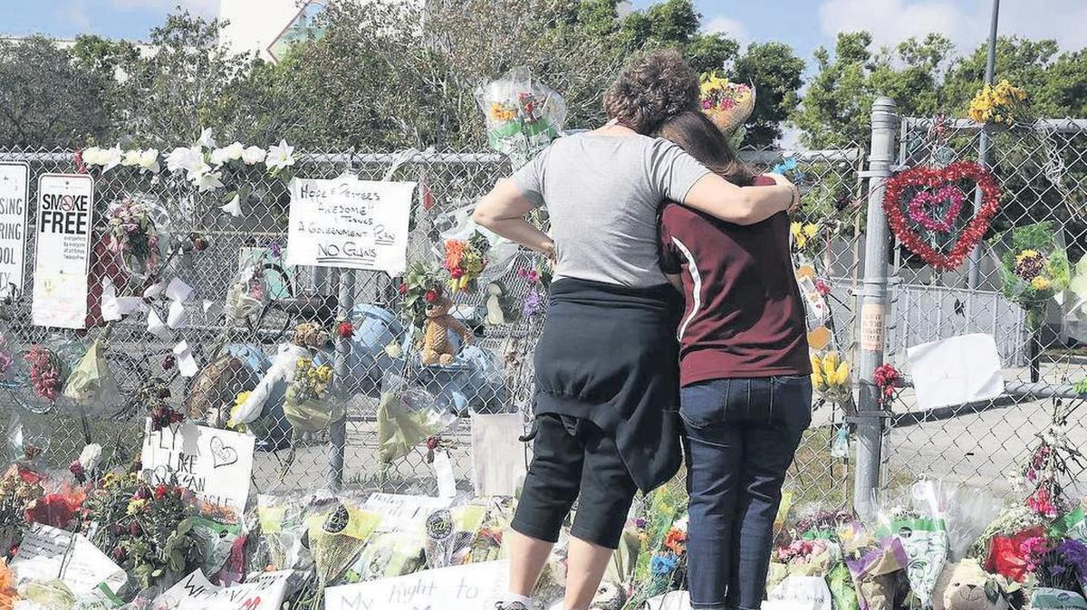 Dos empleadas de la secundaria Marjory Stoneman Douglas rinden tributo a las víctimas del tiroteo cuando la escuela reabrió el 23 de febrero de 2018, nueves días después de la tragedia.