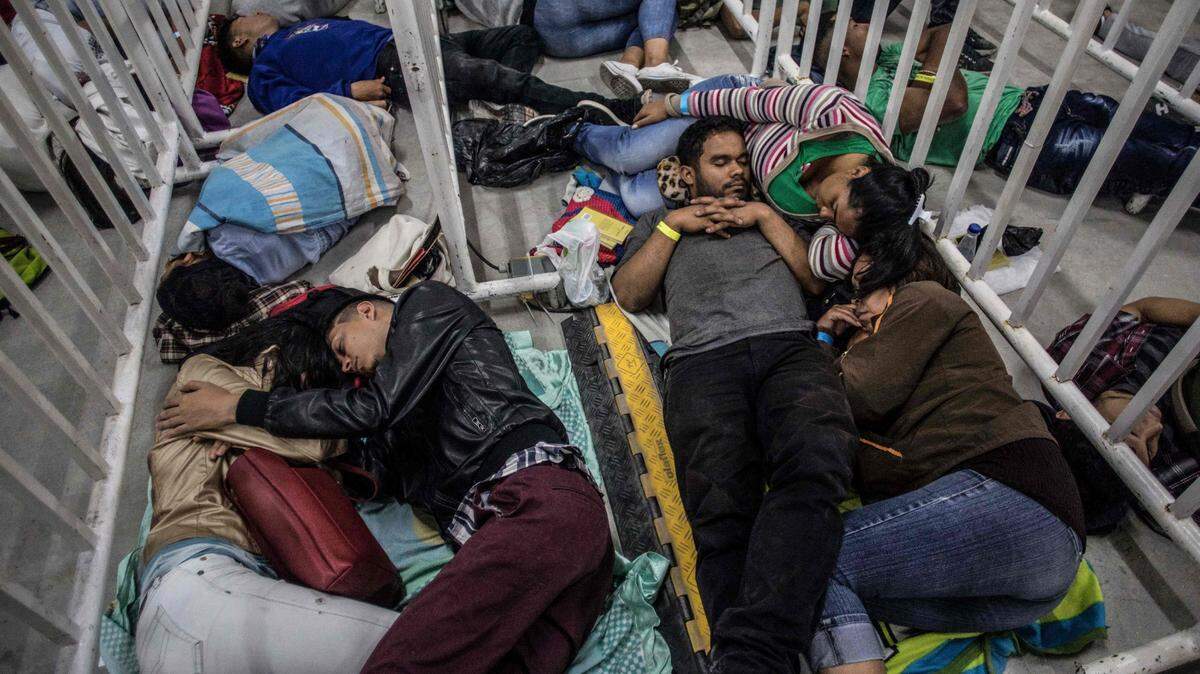 Inmigrantes venezolanos duermen mientras esperan que comience una feria de trabajo el 27 de septiembre de 2018, en Medellín, Colombia.