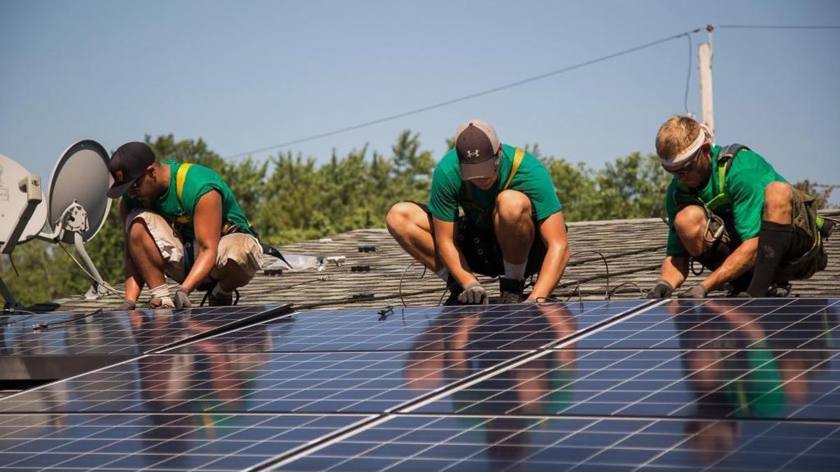 Empleados de SolarCity Corp. instalan paneles solares en una casa.
