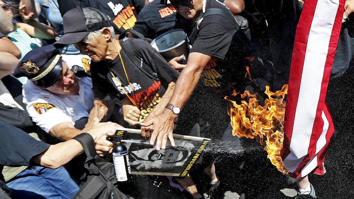 Un policía trata de apagar una bandera en llamas durante una protesta en Cleveland, el pasado julio.