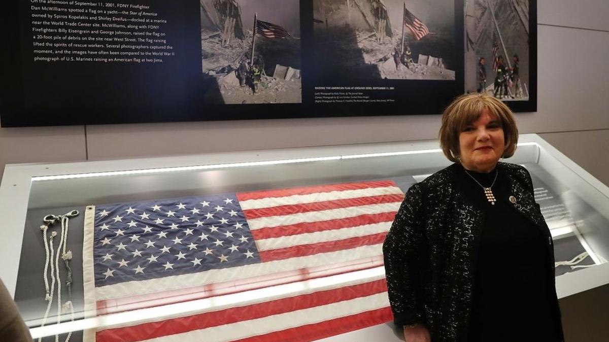 Shirley B. Dreifus posa en el Museo del 9/11, en Nueva York, junto a la bandera que los bomberos izaron sobre las ruinas del World Trade Center el día del ataque. La bandera pertenecía a Dreifus.