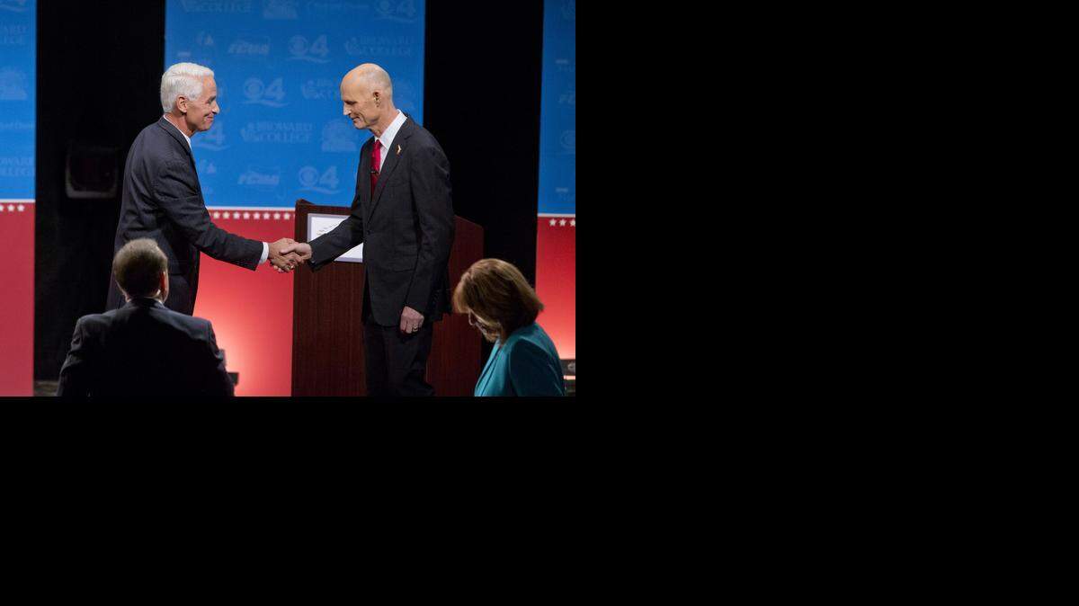 El gobernador de la Florida, Rick Scott (der.), y el retador Charlie Crist se dan la mano tras un debate en Davie, el miércoles pasado.
