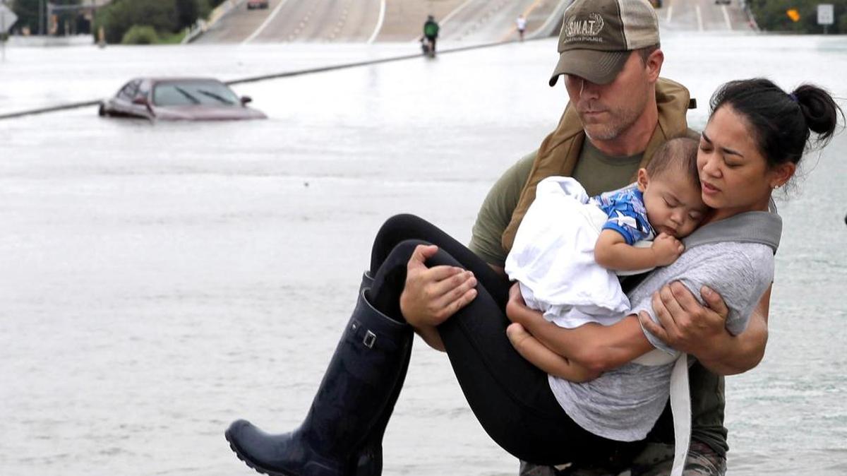 Daryl Hudeck, del equipo SWAT de la policía de Houston, pone a salvo a Catherine Pham y a su bebé de 13 meses, Aiden, después de rescatarlos de su casa inundada.