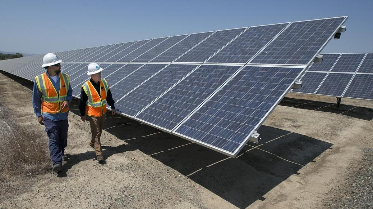Dos técnicos pasan junto a paneles solares en una planta eléctrica en Dixon, California.