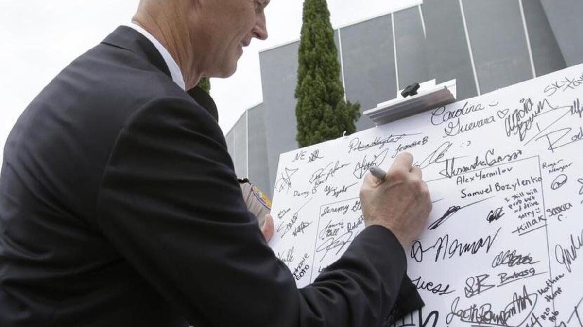 El gobernador de la Florida, Rick Scott, firma una promesa de no enviar mensajes de texto al conducir, en un cartel en la escuela secundaria Alonzo and Tracy Mourning, en North Miami, en mayo del 2013.
