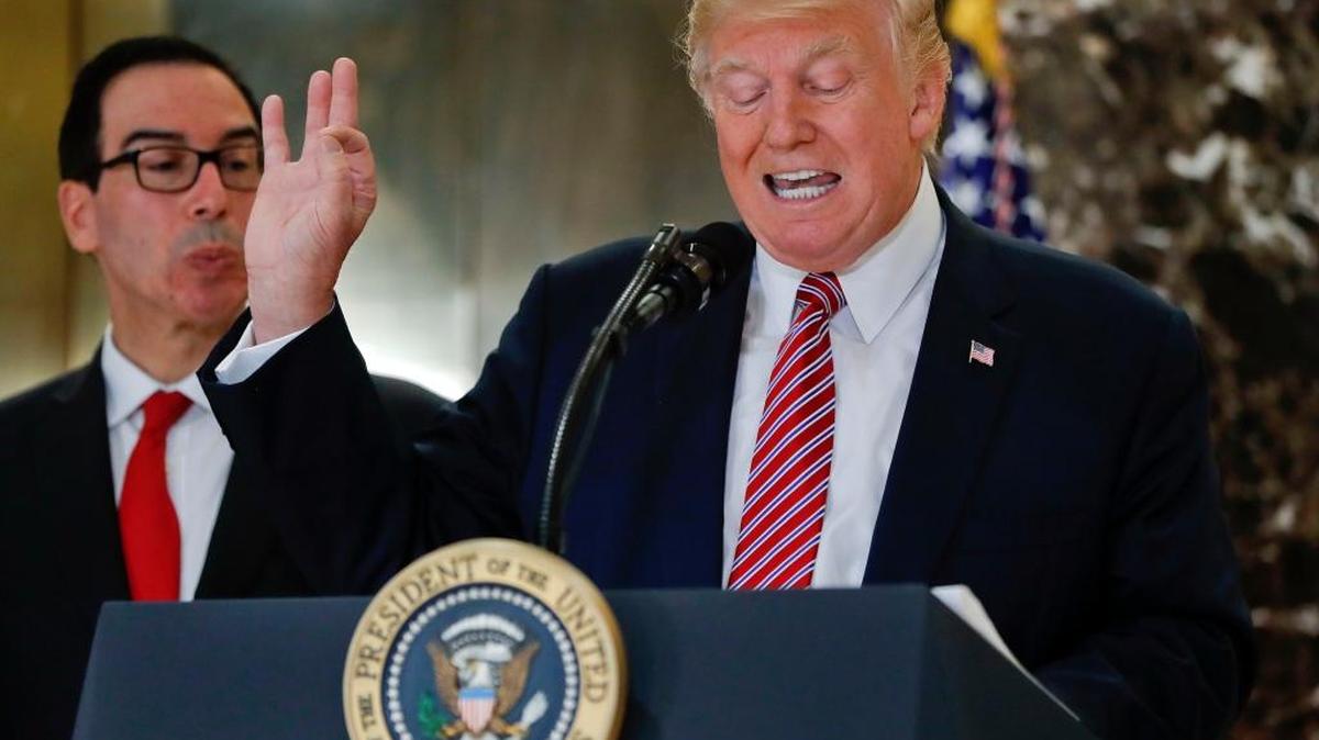 El presidente Donald Trump lee una declaración sobre los sucesos en Charlottesville, Virginia, en el vestíbulo de la Torre Trump, en Nueva York, el martes pasado. A su lado, el secretario del Tesoro, Steve Mnuchin.