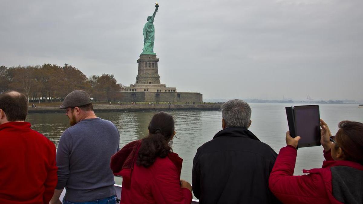 Desde un trasbordador, un grupo de visitantes observa la Estatua de la Libertad, en Nueva York.