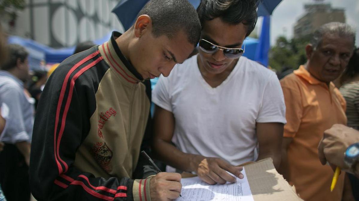 Un joven firma en Caracas una petición de referendo revocatorio contra el presidente Nicolás Maduro.