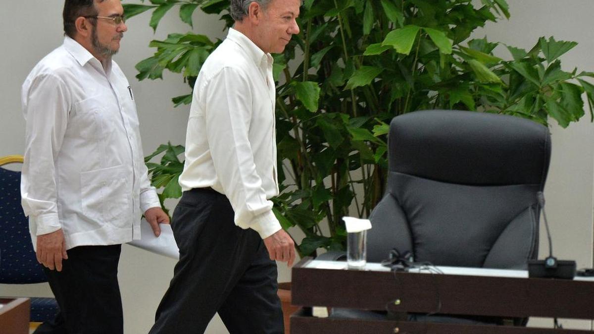 El presidente de Colombia, Juan Manuel Santos (der.) y Timoleón Jiménez, el jefe de las FARC, se disponen a firmar el acuerdo de paz en La Habana.