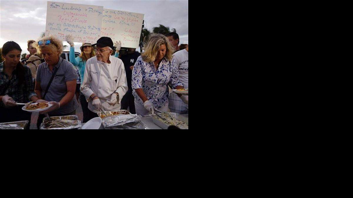 
Arnold Abbott (centro), ayudado por voluntarios, sirve comidas a los desamparados en la playa de Fort Lauderdale.
 