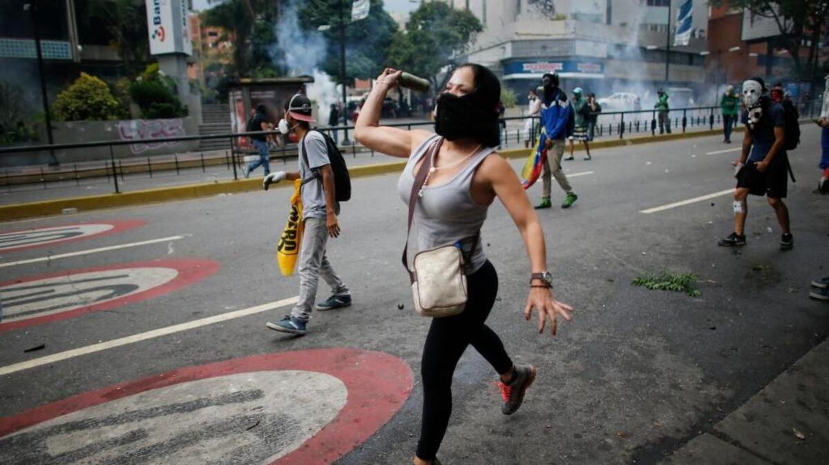 Una mujer lanza una botella durante protestas contra el gobierno en Caracas, el jueves.