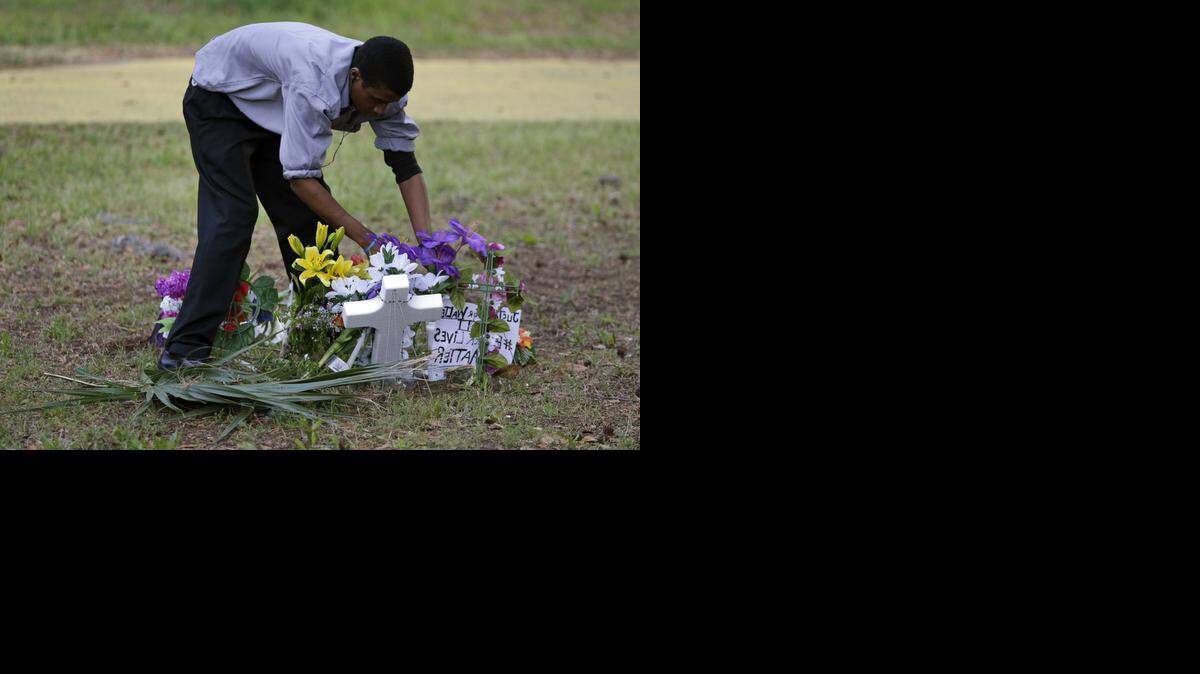 
Un hombre no identificado arregla las flores colocadas en recuerdo de Walter Lamer Scott, abatido por un policía en North Charleston.
