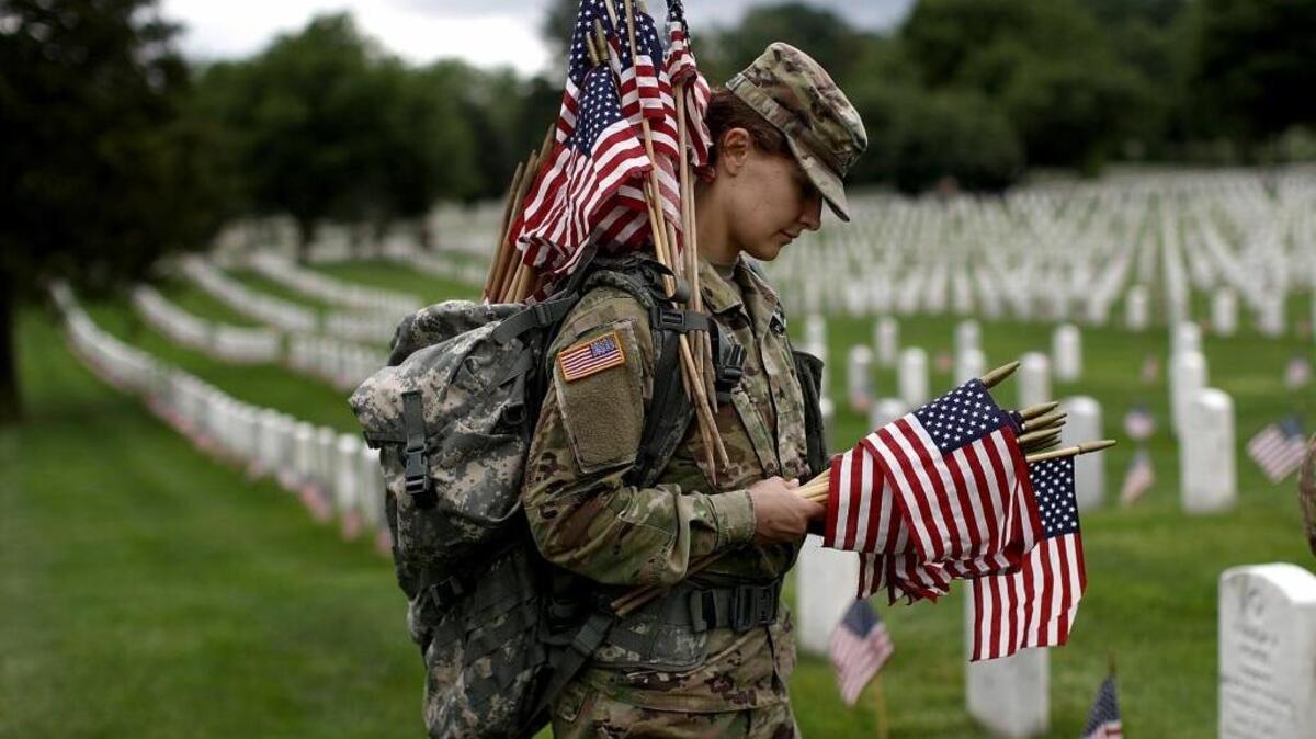 La sargento Iwona Kosmaczewska coloca banderas en las lápidas de soldados norteamericanos en el Cementerio Nacional de Arlington, el pasado 25 de mayo.