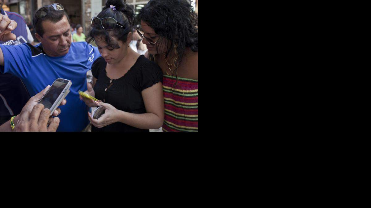 
Cubanos tratan de conectarse con un servidor para hablar por teléfono móvil frente a las oficinas del monopolio estatal telecom (Etecsa) en Miramar.


