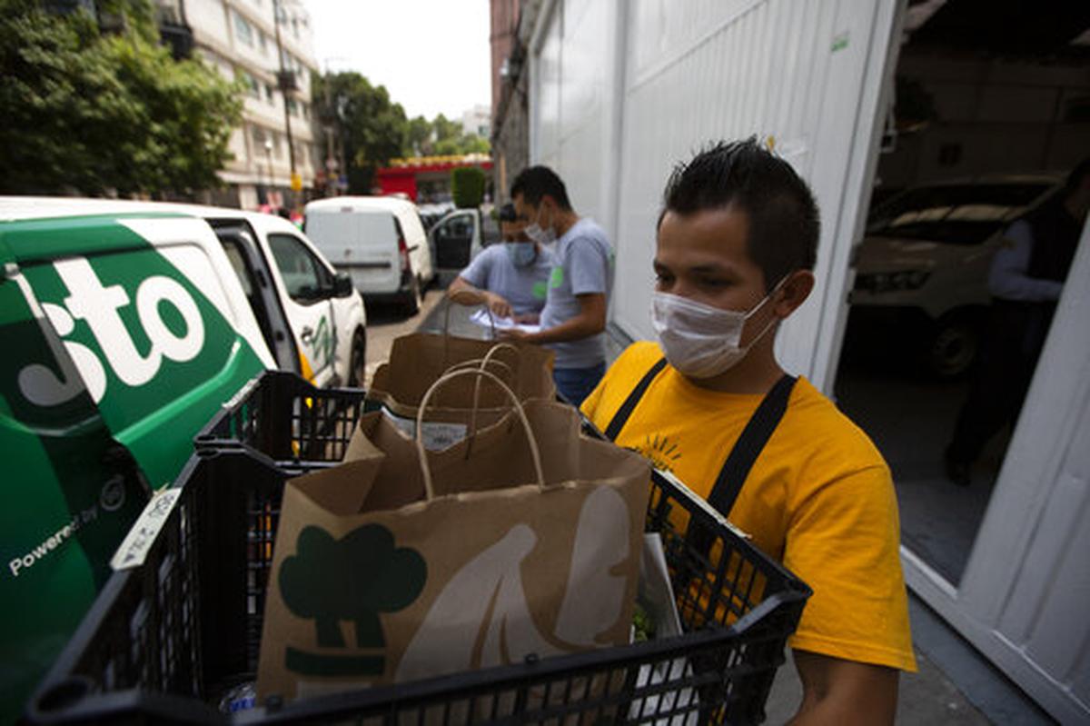 A supermarket employee loads groceries onto a vehicle in Mexico City on Friday, April 24, 2020.