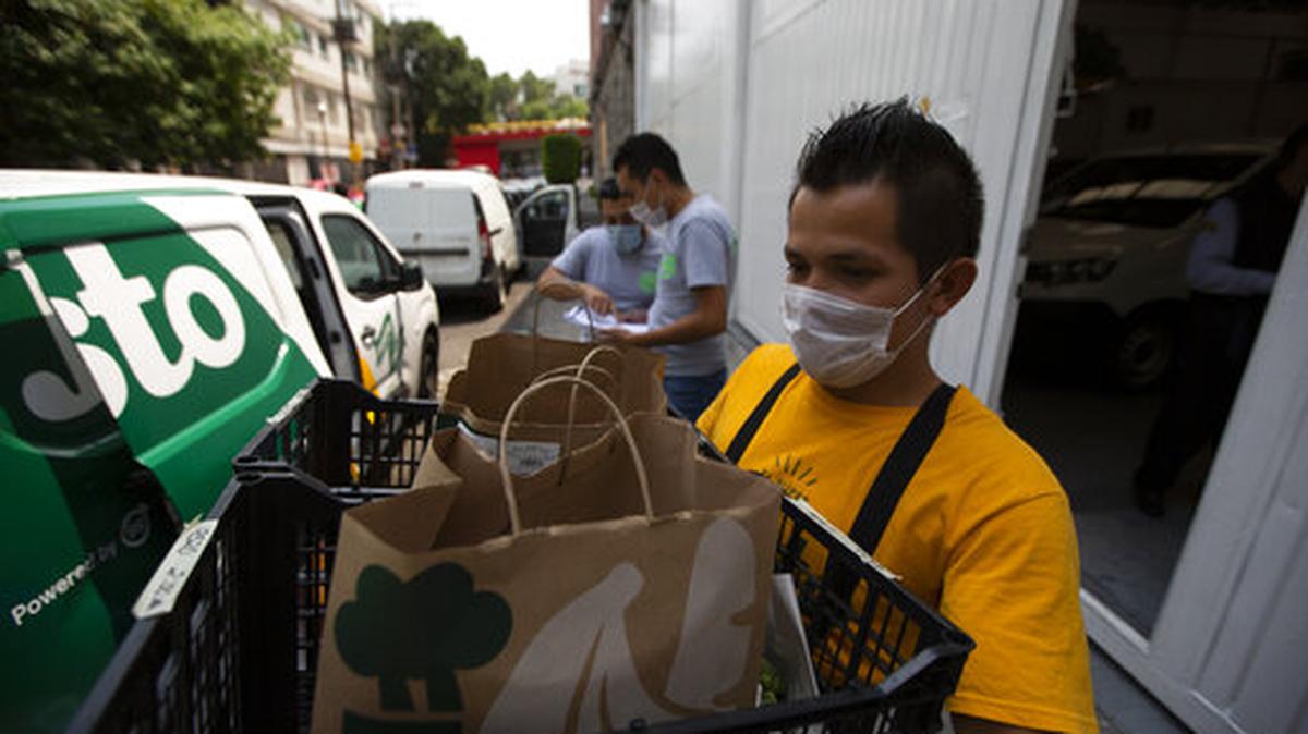 Un trabajador carga comestibles en una camioneta afuera del almacén de Justo, un supermercado en línea en la Ciudad de México, el viernes 24 de abril de 2020.