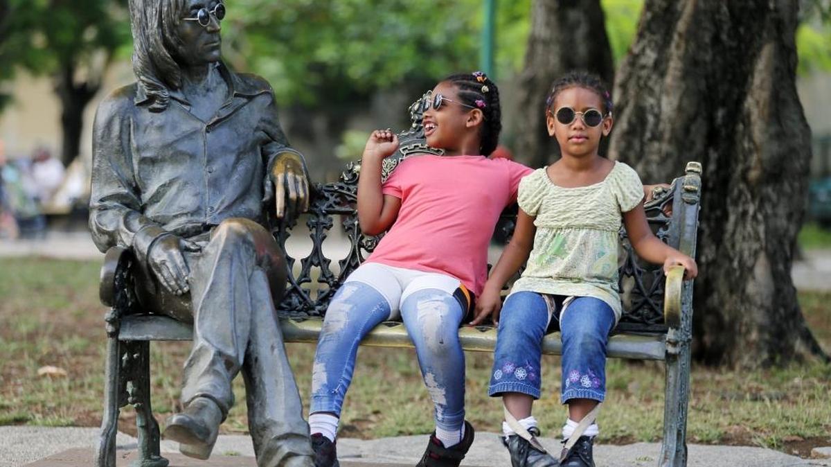 Dos niñas se sientan junto a la estatua del John Lennon, en un parque de La Habana. El domingo se cumplen 76 años del nacimiento del famoso Beatle.