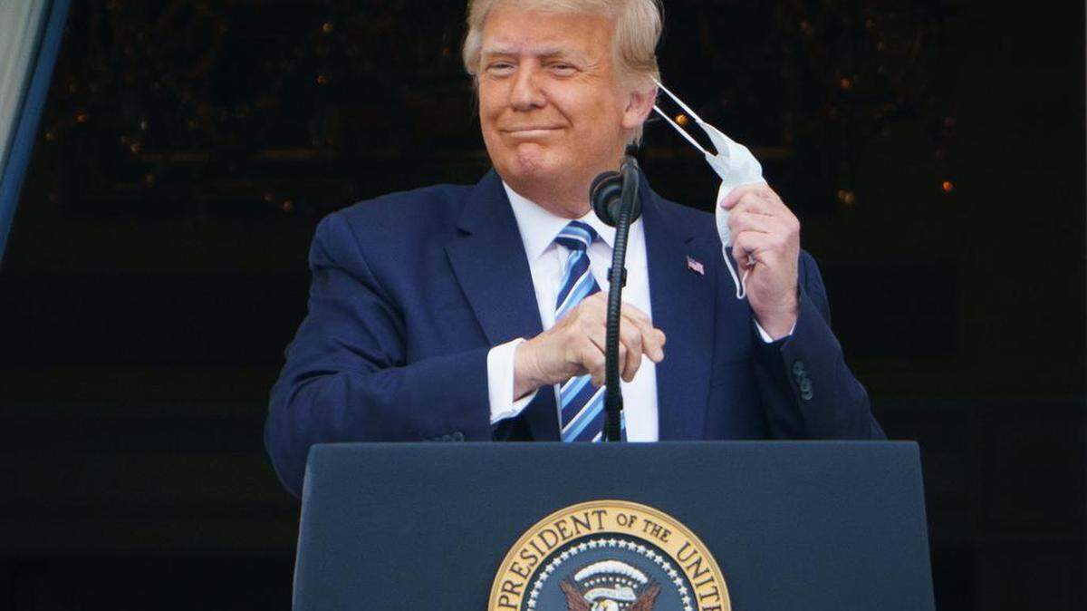 El presidente de Estados Unidos, Donald Trump, se quita la máscara antes de hablar desde el pórtico sur de la Casa Blanca en Washington, DC durante un mitin, el sábado 10 de octubre de 2020.