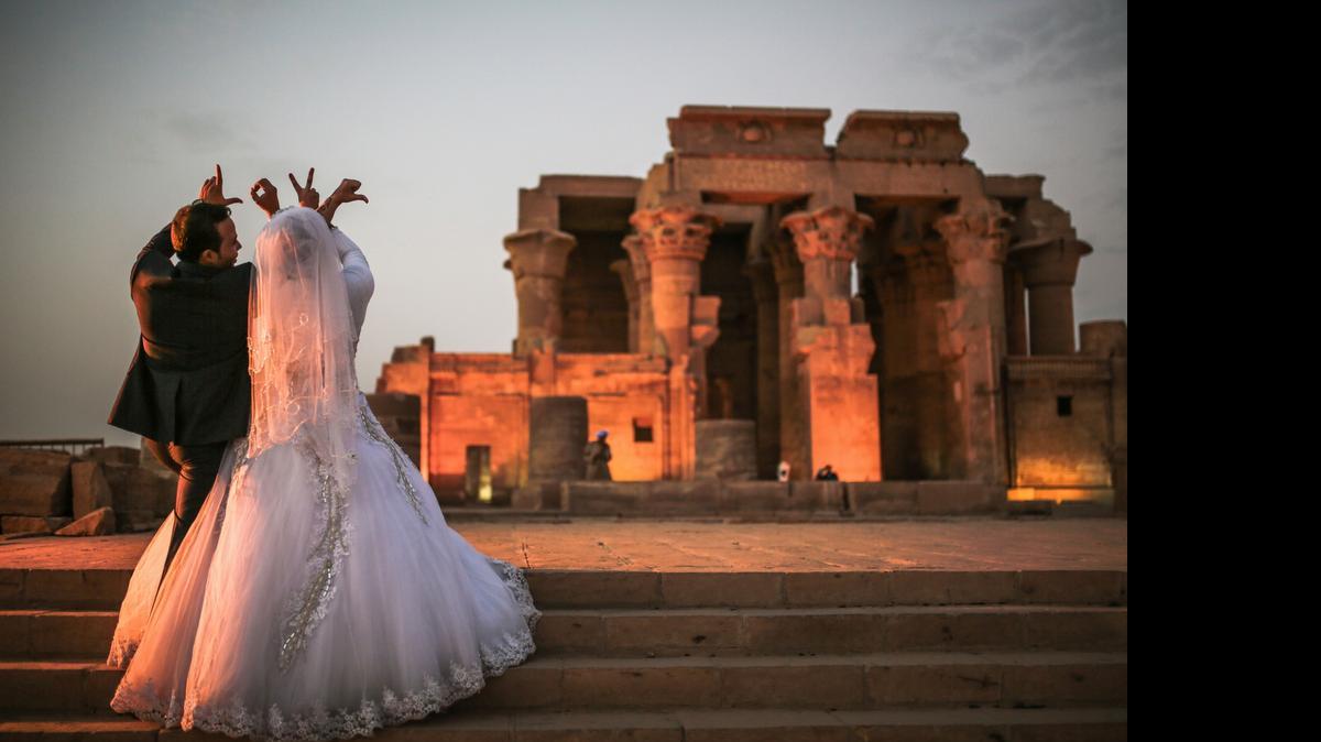 
Una pareja de recién casados forma con sus manos la palabra “love” (amor) frente al templo de Kom Ombo, en el sur de Egipto.
