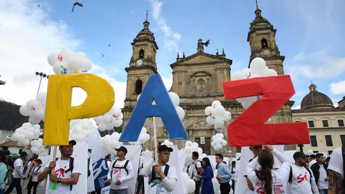 Colombianos sostienen un letrero por la paz en la Plaza Bolívar en Bogotá, el lunes 26, cuando el gobierno y las FARC firmaban el acuerdo de paz para terminar un largo conflicto.