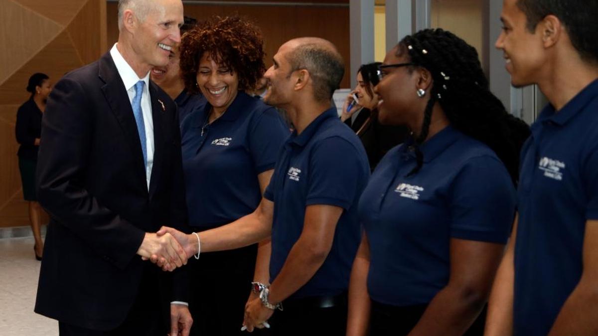 El gobernador de la Florida, Rick Scott (izq.) saluda a un grupo de estudiantes del Miami Dade College el 28 de junio.