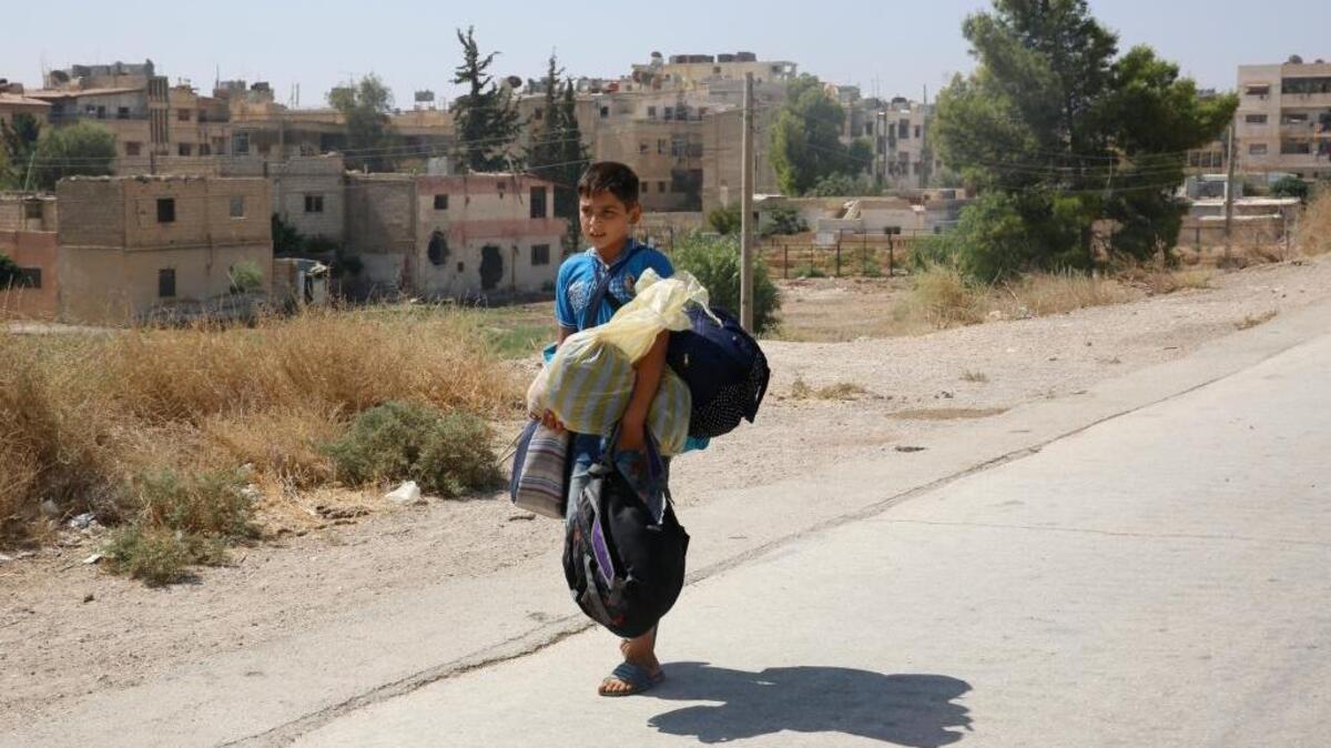 Un niño abandona con sus escasas pertenencias el asediado suburbio de Moadamiyeh, en Damasco, la capital de Siria, el viernes pasado, mientras el país sufre la devastación de la guerra.