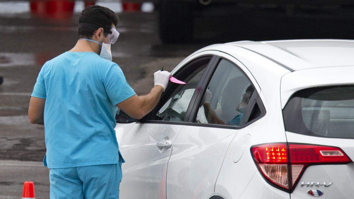 Un especialista médico toma la información de un conductor que quiere hacerse el examen del coronavirus, el domingo 22 de noviembre de 2020, en el centro ambulante de pruebas en el Hard Rock Stadium de Miami Gardens.