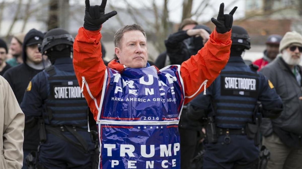 Detrás de una fila de policías con equipos antimotines, un hombre muestra su apoyo al presidente Donald Trump en una concentración en Olympia, en el estado de Washington, el 4 de marzo.