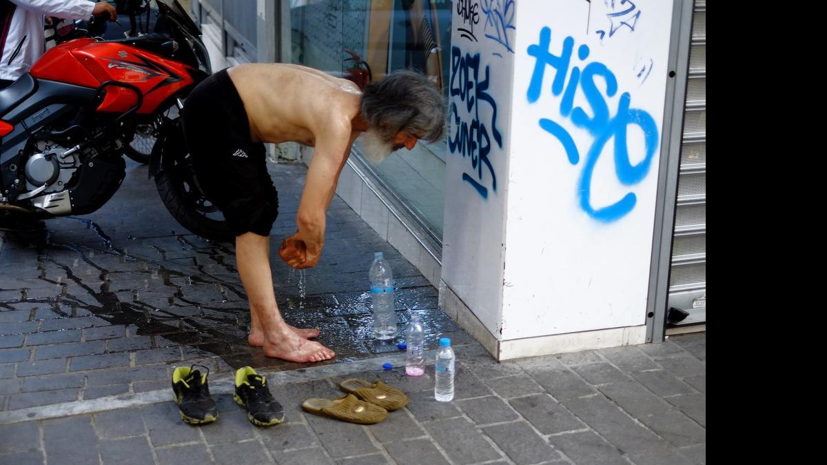 
Un desamparado se lava las manos y los pies en el centro de Atenas, el pasado junio.
