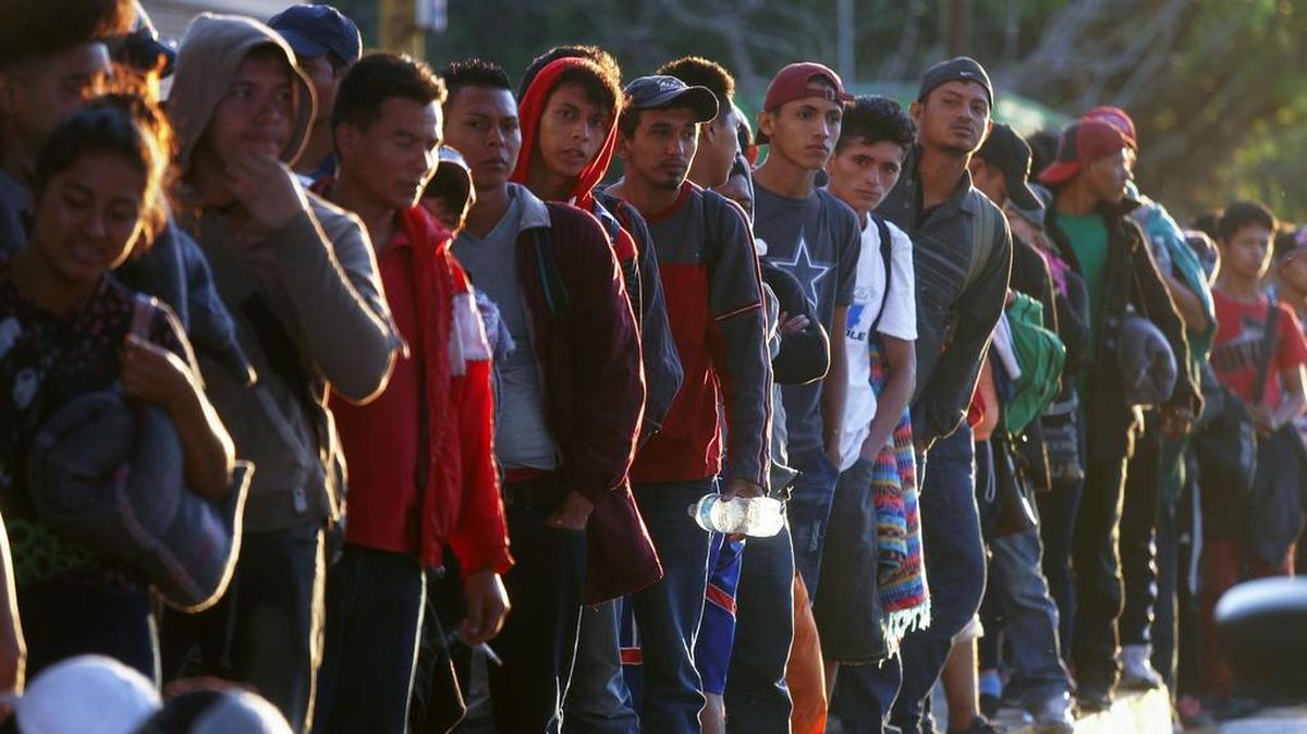 Decenas de inmigrantes esperan a lo largo de una carretera para tratar de conseguir transporte, en su recorrido hacia Estados Unidos, el lunes en Pijijiapan, México