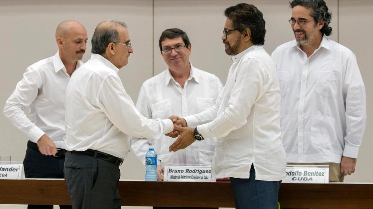 Humberto de la Calle (izq.) jefe de la delegación del gobierno colombiano, saluda a Iván Marquez, dirigente de las FARC, después de firmar en La Habana un acuerdo para compensar a seis millones de víctimas del conflicto en Colombia, el 15 de diciembre.