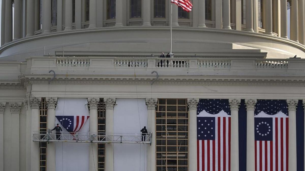 Trabajadores cuelgan una bandera norteamericana en el Capitolio que se usará como parte del decorado para la toma de posesión de Donald Trump y el fin de los ocho año de gobierno de Barack Obama.